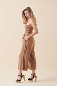 Load image into Gallery viewer, Side view of the Shiloh Smocked Tube Top Jumpsuit in Camel, highlighting the relaxed wide-leg fit, smocked bodice, and functional side pockets.
