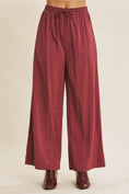 Load image into Gallery viewer, Maroon wide-leg pants with a tie waist on a beige background
