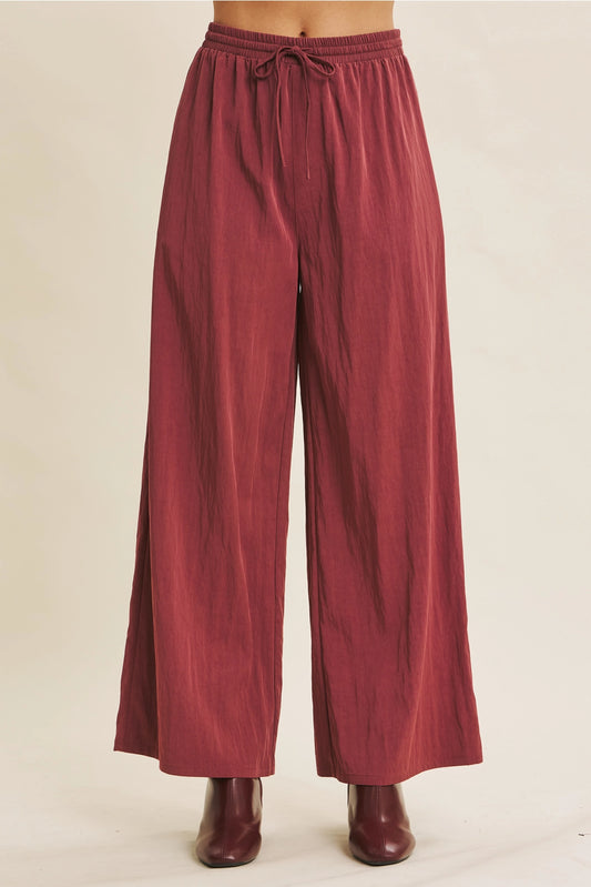 Maroon wide-leg pants with a tie waist on a beige background